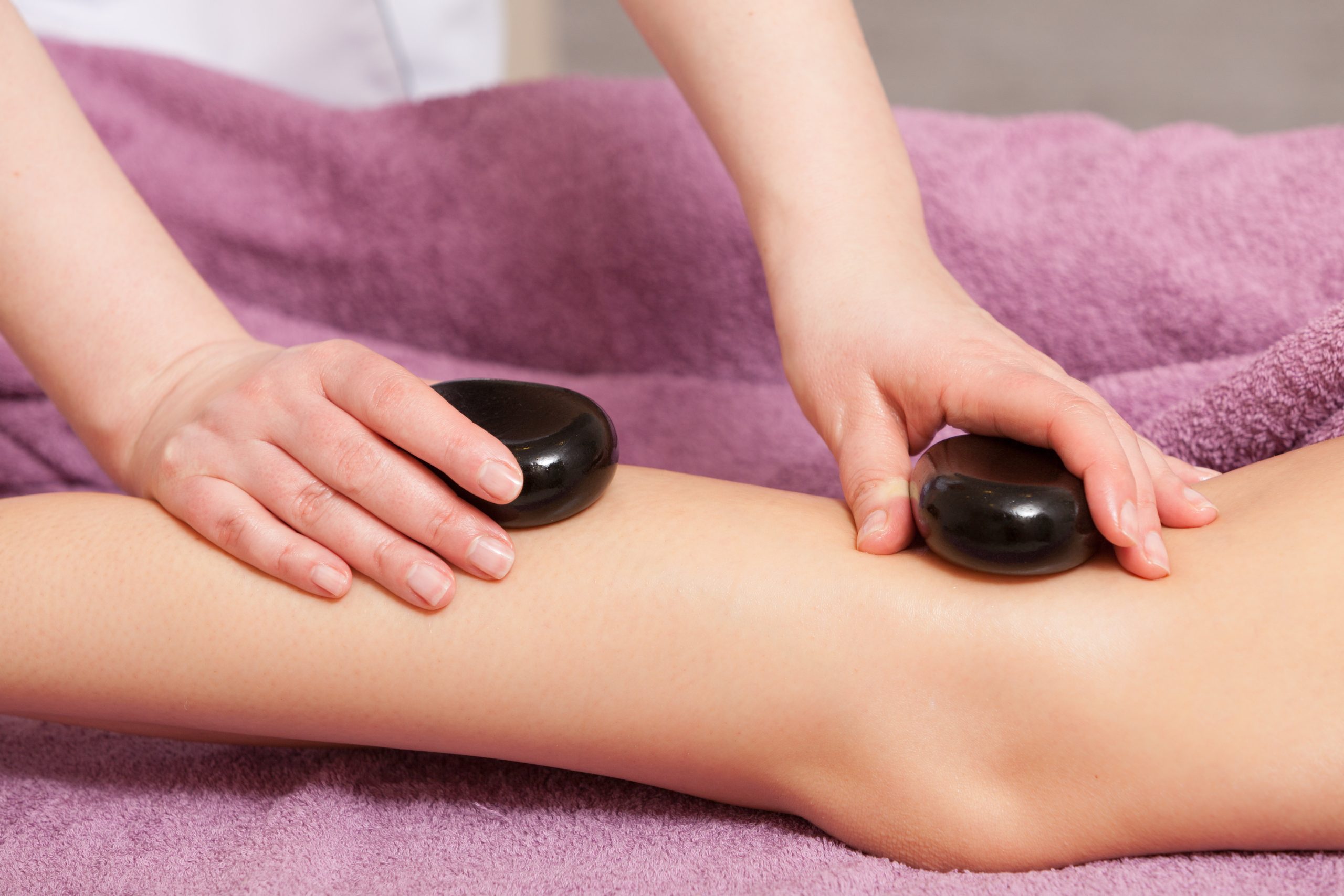 Combination Massage woman having hot rocks placed on her leg